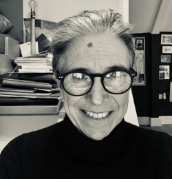 A black and white image of a woman from the shoulders up. She is smiling at the camera.