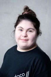 Ophir Yaron. A headshot of a smiling person wearing a black tshirt and with black hair tied up in a messy bun