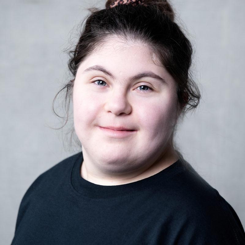 Ophir Yaron. A headshot of a smiling person wearing a black tshirt and with black hair tied up in a messy bun