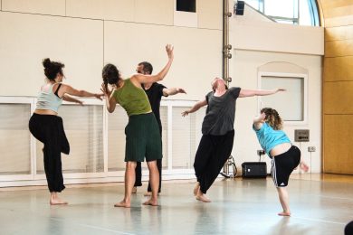A group of people dancing freely in a rehearsal studio.